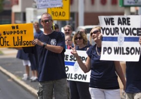 Supporters of officer Darren Wilson hold placards outside Barney's Sports Pub in St. Louis, Missouri