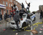 BESTPIX BALTIMORE, MD - APRIL 27:  Demonstrators climb on a destroyed Baltimore Police car in the street near the corner of Pennsylvania and North avenues during violent protests following the funeral of Freddie Gray April 27, 2015 in Baltimore, Maryland. Gray, 25, who was arrested for possessing a switch blade knife April 12 outside the Gilmor Homes housing project on Baltimore's west side. According to his attorney, Gray died a week later in the hospital from a severe spinal cord injury he received while in police custody.  (Photo by Chip Somodevilla/Getty Images) *** BESTPIX ***