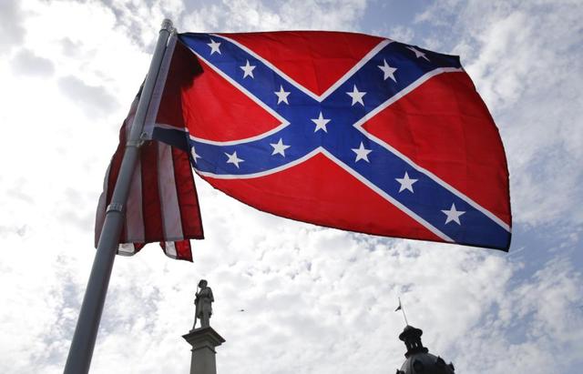 A protester waves a Confederate battle flag in front of the South Carolina statehouse, Thursday, July 9, 2015, in Columbia, S.C. More than 50 years after South Carolina raised a Confederate flag at its Statehouse to protest the civil rights movement, the rebel banner is scheduled to be removed Friday morning during a ceremony. (AP Photo/John Bazemore)